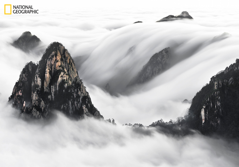 Captured this image  in early morning  in the Yellow Mountain  China . Behind this image is a story , climbing at 3 am  to reach the point of shooting , when I arrived  I could  see in the complete dark  the effect of the white and slow motion of this cloud waterfall . My hope was when the sunrise  come out  this effect of the nature will still stand  front of me . Lucky at 6.30 am the effect was still there the time I took the shot before it disappear  completely few minutes later  .