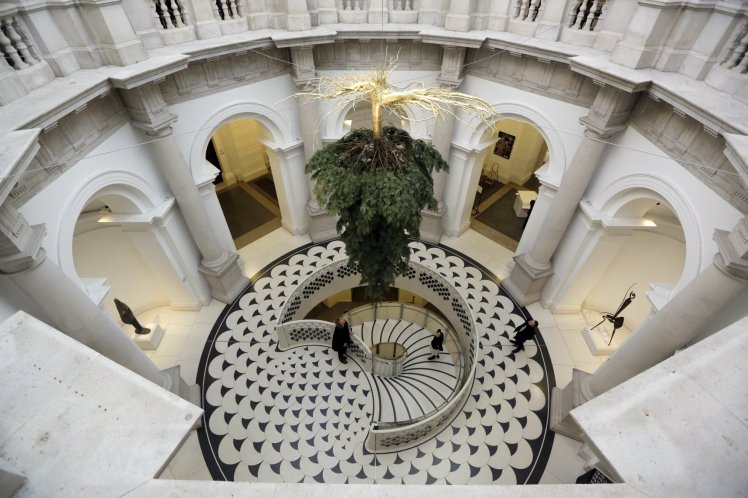 Staff members pose for photographs at the unveiling of a Christmas tree by Iranian-born artist Shirazeh Houshiary, in the Rotunda at Tate Britain gallery in London, Thursday, Dec. 1, 2016. The tree is part of the gallery's annual festive commissions and the first for a few years after the gallery space was renovated. (AP Photo/Matt Dunham)